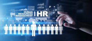 Graphic of a human hand reaching toward a digital interface that reads, “Human Resources Management | HR,” superimposed over various graphs and charts, a map of the earth, and a line of individuals.