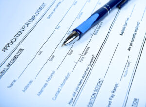 Close-up of an employment application, with a blue ballpoint pen resting on top of it.